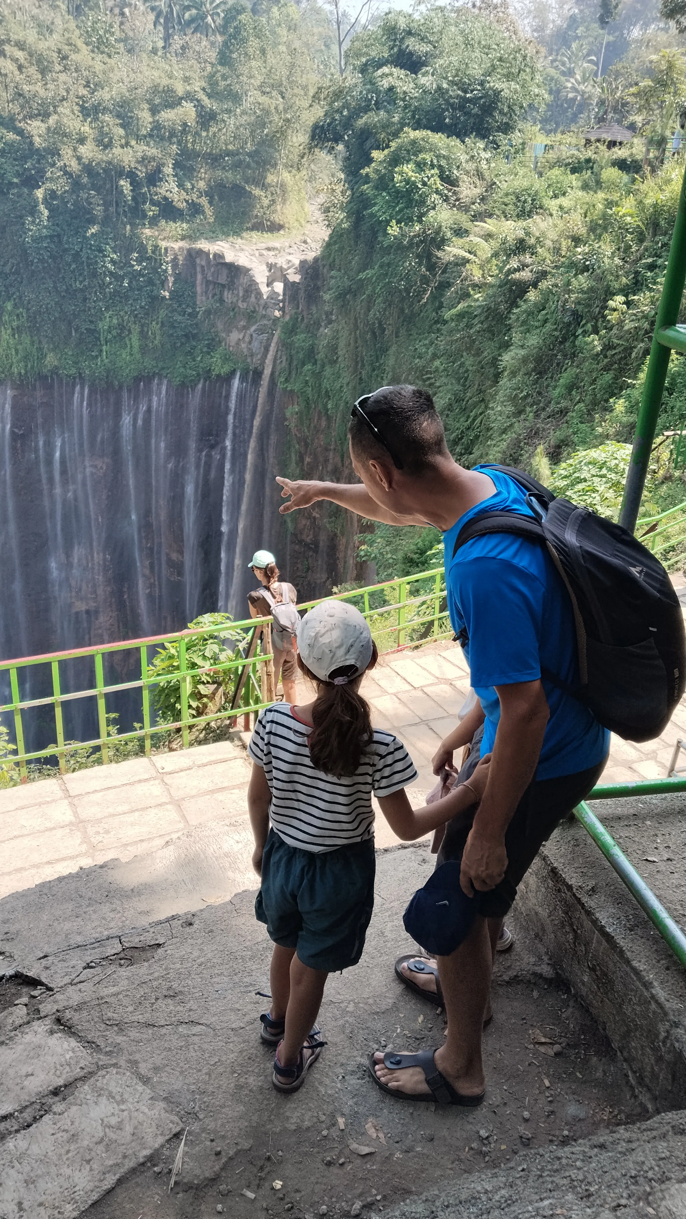 A father showing his children the scenery of Tumpak Sewu Waterfall in East Java.